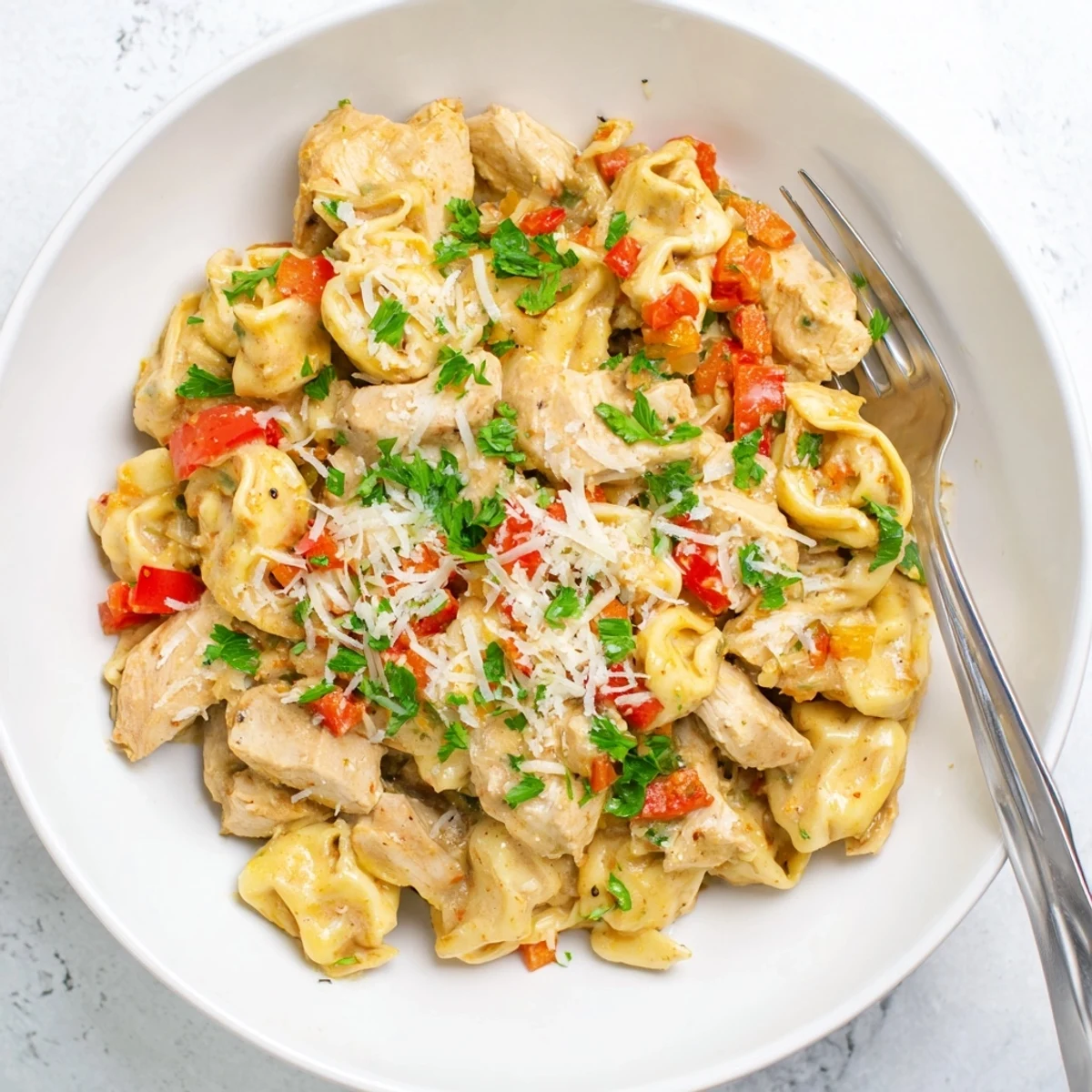 Creamy Zesty Cajun Garlic Parmesan Chicken Tortellini garnished with fresh parsley and cheese.  