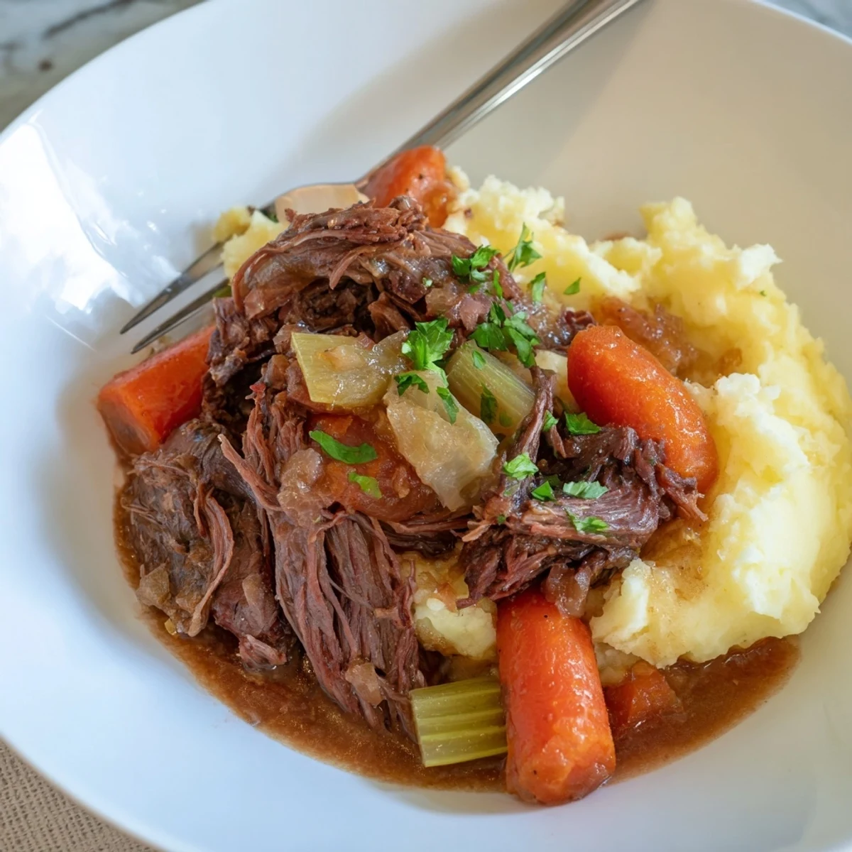 Tender Slow Cooker Pot Roast with Mashed Potatoes, garnished with fresh parsley and rich gravy.  
