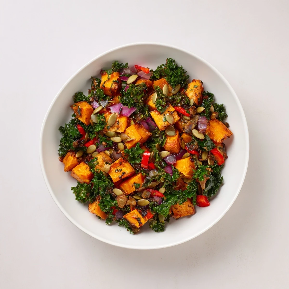 Perfectly plated, steaming-hot Maple Glazed Sweet Potato & Kale Hash topped with fresh parsley and pumpkin seeds.