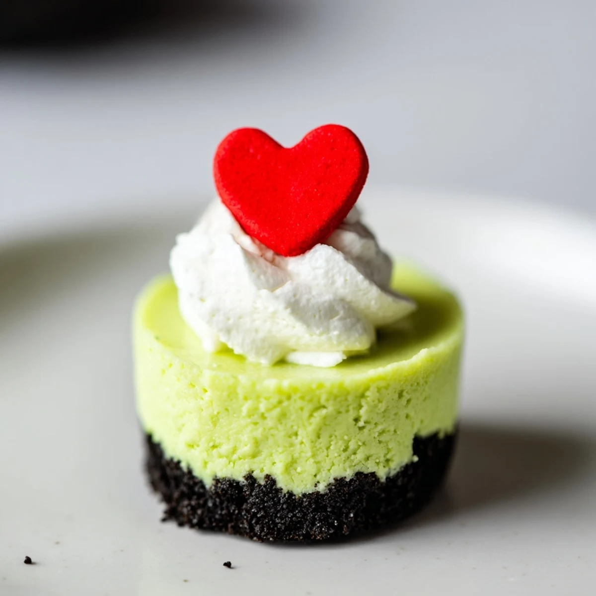 Vibrant green Grinch Mini Cheesecakes, topped with whipped cream and festive red sprinkles, look so delicious!