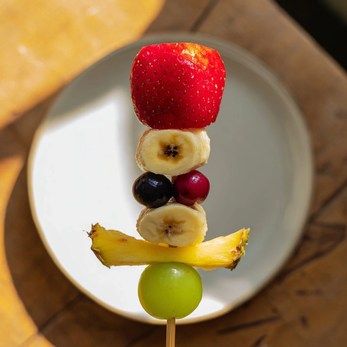Rocket ship fruit skewers stand upright, showcasing strawberries, grapes, and pineapple in fun shapes.