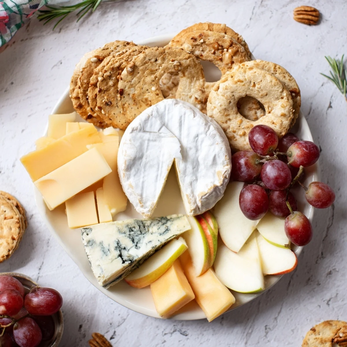 This Cheese Plate showcases colorful grapes, fruit slices, and a drizzle of honey beside the cheeses.