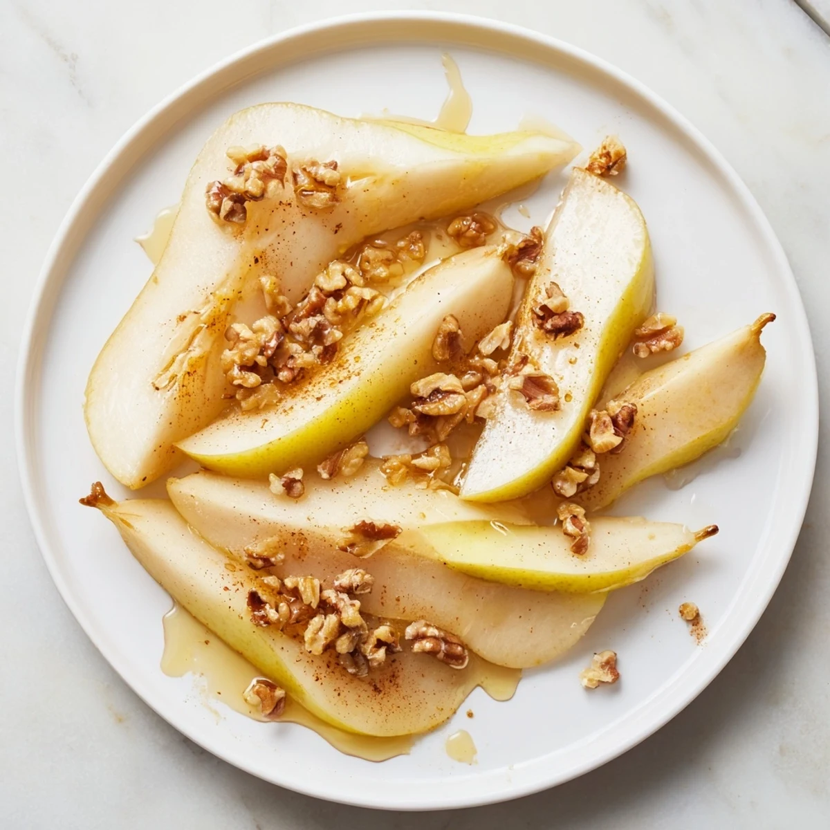 Appetizing pear slices arranged on a plate, finished with honey and a sprinkle of cinnamon.