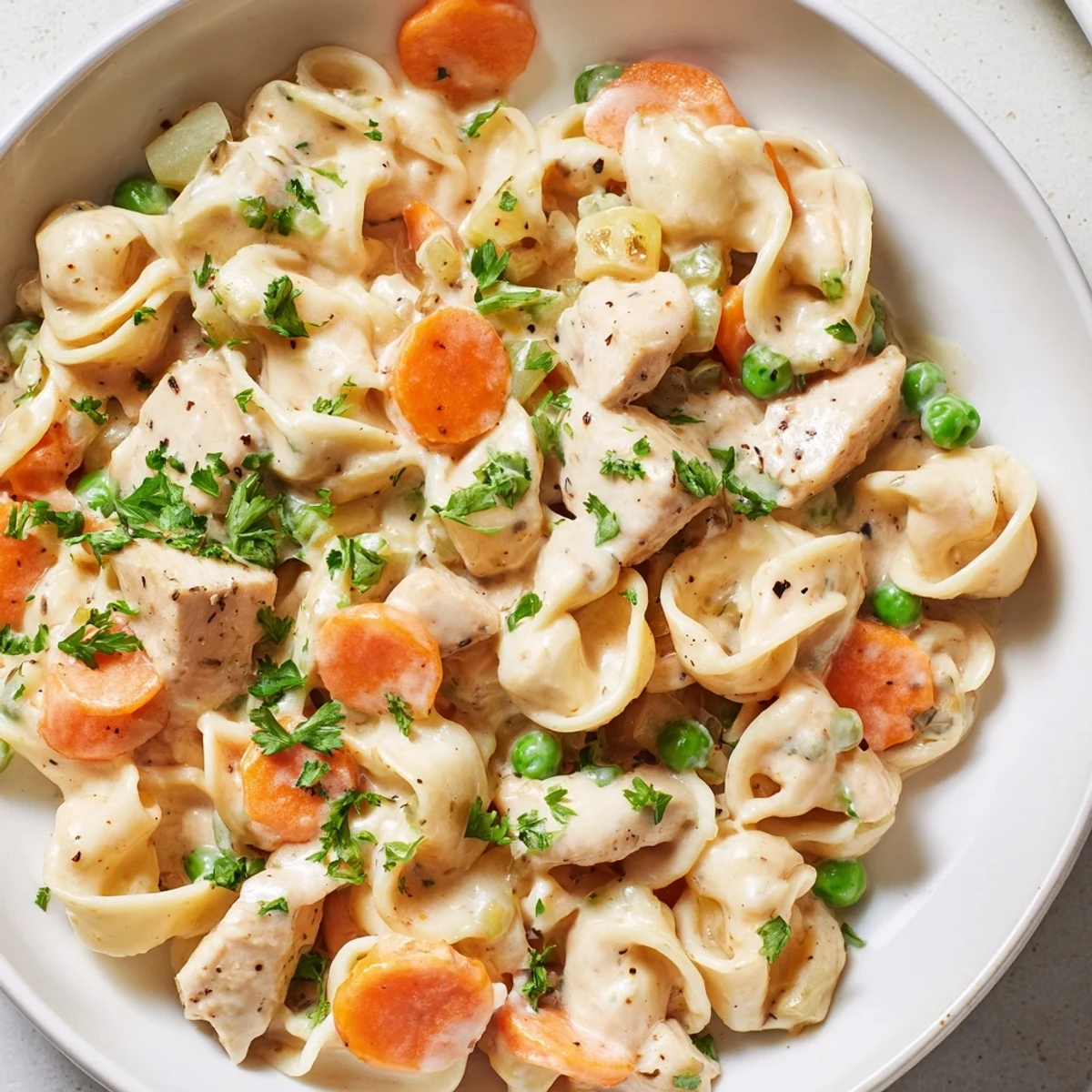 Steaming creamy chicken and egg noodles, a hearty American dinner with fragrant herbs and veggies.