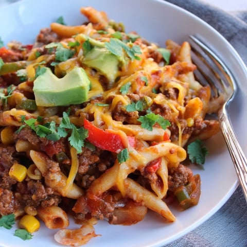 Creamy, cheesy Budget One-Pot Taco Pasta, garnished with fresh cilantro and a dollop of sour cream.