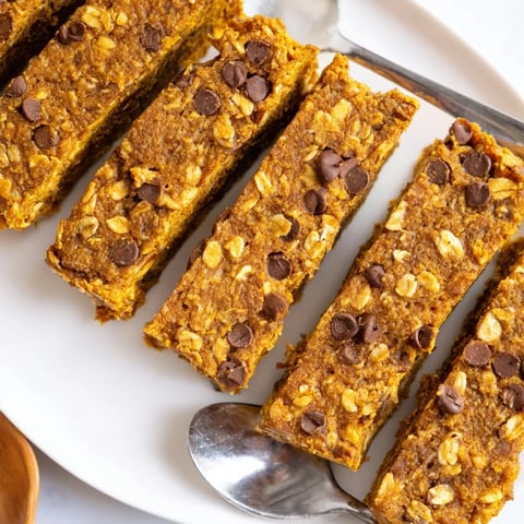 Moist pumpkin muffin protein bars topped with chocolate chips and walnuts for indulgence.