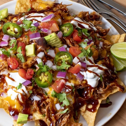 Crispy tortilla chips topped with BBQ pulled pork and melted cheese, perfect for sharing.  