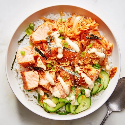 Crispy salmon rice bowl topped with spicy mayo, kimchi, and fresh avocado slices.  