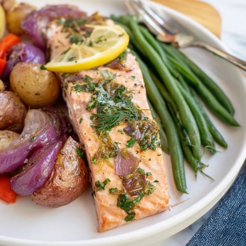 Lemon Herb Salmon & Potato Sheet Pan dish surrounded by colorful roasted veggies.