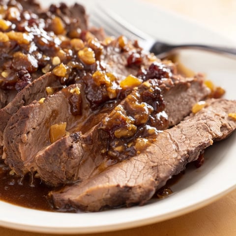 Tender Sauerbraten Style Pot Roast simmering in rich, aromatic gravy with spices.