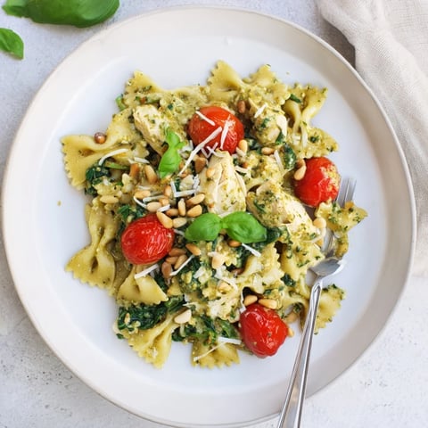 Creamy pesto chicken bowtie pasta garnished with fresh basil and toasted pine nuts.  