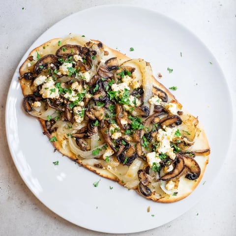 Warm Caramelized Onion & Mushroom Flatbread, topped with melted cheese, ready to eat.