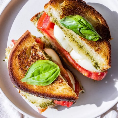 Golden-brown Caprese Pesto Panini-Style Grilled Cheese, oozing with melted mozzarella and fresh basil pesto.