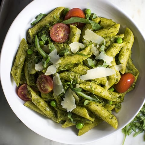 One-Pot Creamy Pesto Pea Protein Pasta: a steaming plate of pasta with vibrant pesto and tomatoes.