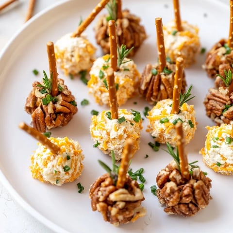 Savory acorn shaped cheese ball bites, rolled in nuts and herbs, ready for a fall appetizer.