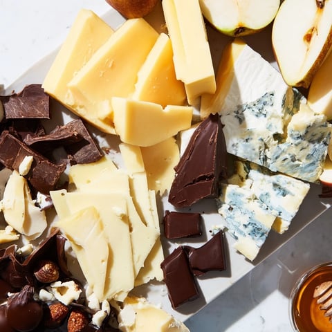 A vibrant platter filled with Fireside Comfort & Cocoa, cheeses, chocolates, and inviting fruit slices.