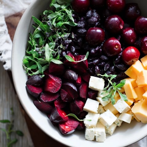 Vibrant, festive Holly Berry Cluster platter with red berries, cheeses, and fresh green herbs.